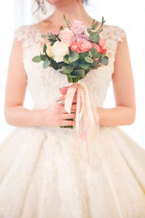 Young beautiful brunette woman with bouquet posing in a wedding dress. Close upの写真素材