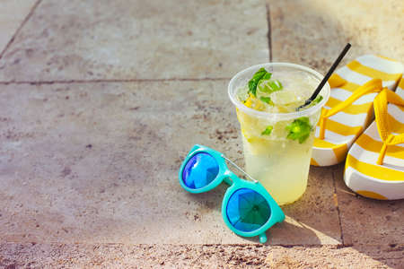 Sunglasses, flipflops and mojito glass on stone backgroundの写真素材