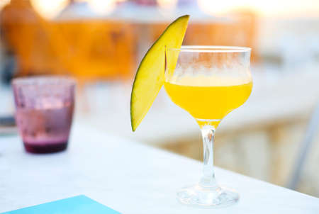 Glass of mango cocktail on bar counter outdoorsの写真素材