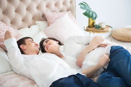 Portrait of the pregnant woman and young man together indoorsの写真素材