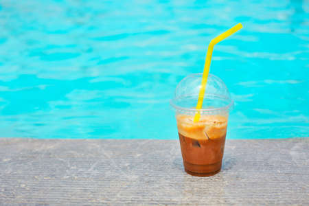 Iced coffee glass on outdoor poolside 