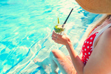 Young woman with glass of lemonade near the pool