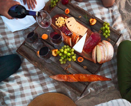 People drinking red wine outdoor. Summer picnic on the beach. Top view. Picnic
