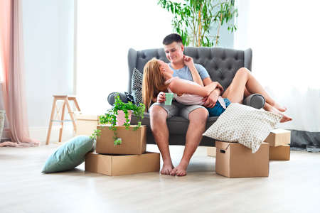 Young happy couple in room with moving boxes at new home