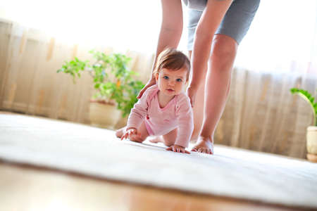 Baby girl playing with mother in the roomの写真素材