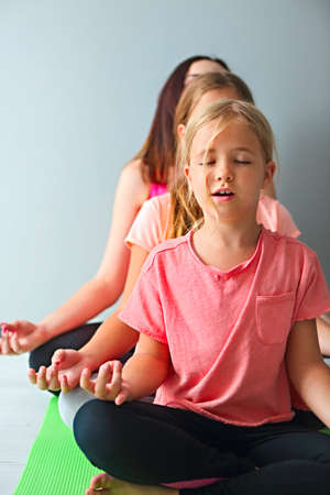 Young woman having fun with kids doing yoga. Family sport concept