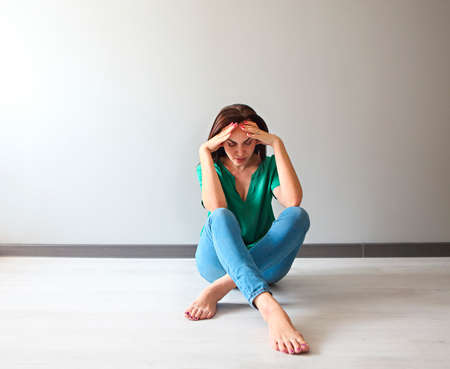 Portrait of a sad woman looking thoughtful about her troubles in front of a gray wallの写真素材