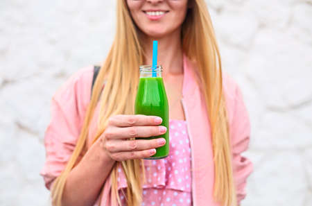 Diet nutrition with detox juice. Healthy woman posing with fresh juice bottle of  green detox smoothie. Closeup of happy beautiful fit girl with fresh juiceの写真素材