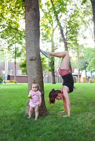 Young woman exercising with her baby girl in the park