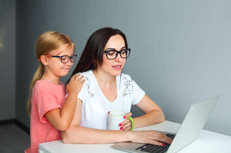 Busy mother working from home with little daughterの写真素材