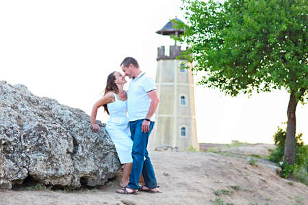 Happy couple posing on a summer day under a tree. Lighthouse on the backgroundの写真素材