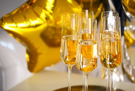 Close up of shiny glasses of champagne over black, white, golden and silver balloons backgroundの写真素材