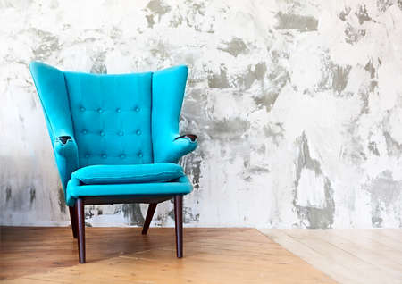 One blue armchair against a white and gray wall and wooden floor. Copy spaceの写真素材