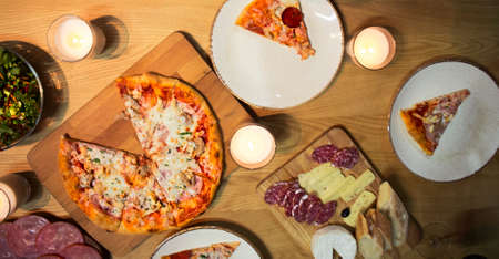 Table with various food served with red wine and candlesの写真素材