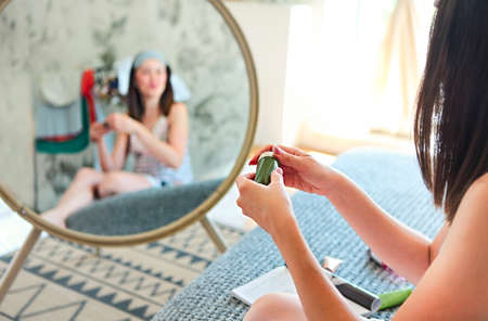 Cute smiling woman applying cream in the morning in the bedroom. Close upの写真素材
