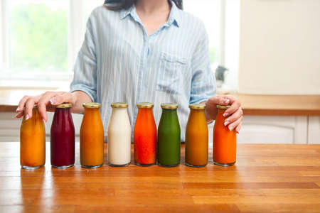 Diet nutrition with detox juice. Healthy woman posing with fresh juice bottles of  detox smoothie. Closeup of happy beautiful fit girl In the kitchen の写真素材