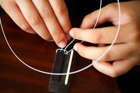 Tuning the string of ukulele, human hands, closeup. Process of changing string of ukulele