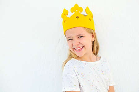 Cute little girl with blonde hair. Little girl with a crown on her head on a white background....