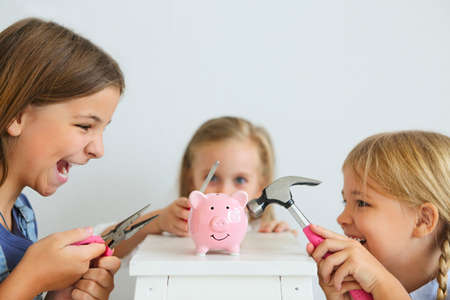 Kids with screwdriver, pliers and hammer by the pink pig piggy bank on a white backgroundの写真素材