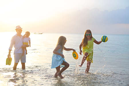 Happy young family have fun on beach run and jump at sunsetの写真素材