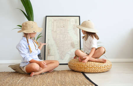 Two little girls are playing at home to travelers wearing vintage style clothes. Childhood, fantasy,...