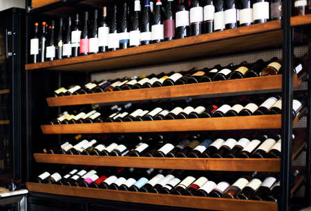 Bottles of wine on the shelves in a rack. Wine shop backgroundの写真素材