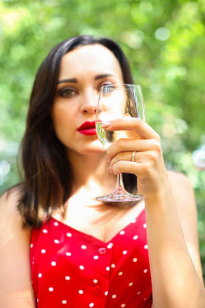 Close up portrait of brunette woman wearing polka dots dress having wine in a restaurant