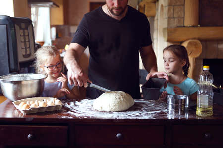Father and his two little helpers. Children cooking homemade bread with their fatherの写真素材