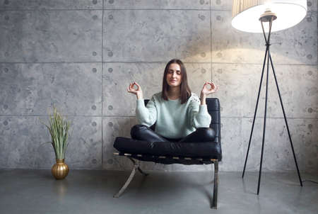 Portrait of attractive brunette woman in green sweater sitting on armchair trying to relaxの写真素材