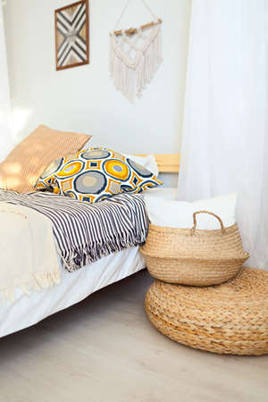 White and beige bedroom in boho style with macrame on the wall