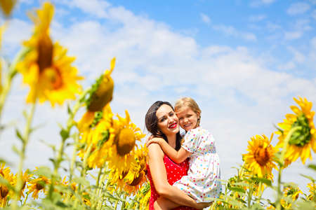 Happy mother and her little daughter in the sunflower fieldの写真素材