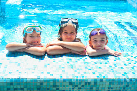 Two cute girls playing in swimming pool. Summer vacation and travel concept