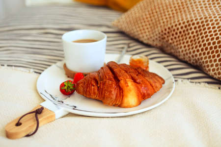 Breakfast with croissant, coffee, strawberry and jam on the plate tray in bed. Top viewの写真素材