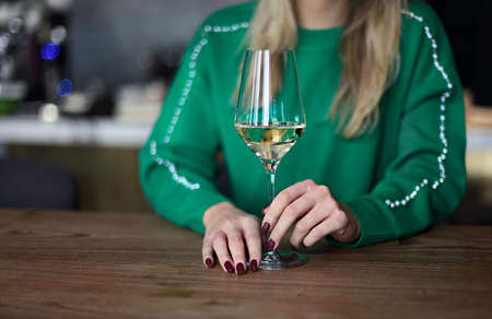 Cropped image of woman holding glass of white wine. Woman in wineryの写真素材