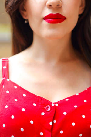 Smiling attractive girl in red polka dots dress in park. Close upの写真素材