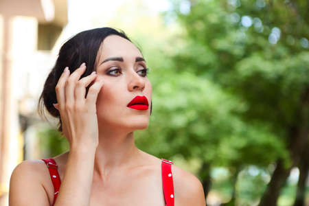 Portrait of the smiling attractive girl in red polka dots dress in parkの写真素材