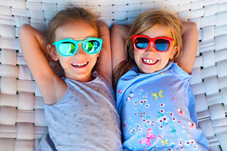 Two little happy girls playing on hammock in summer dayの写真素材