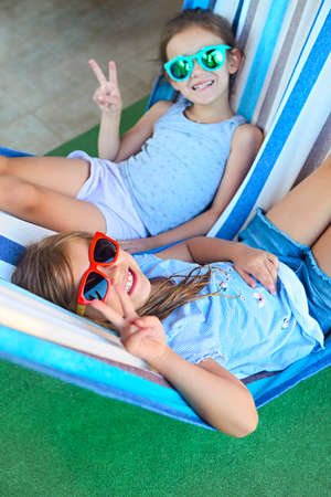 Two little happy girls playing on hammock in summer dayの写真素材