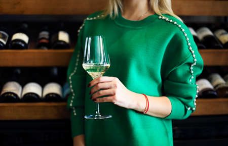 Cropped image of woman holding glass of white wine. Woman in wineryの写真素材