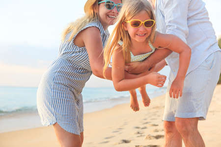Happy family on the beach. People having fun on summer vacation. Father, mother and child against blue sea and beach background. Holiday travel conceptの写真素材