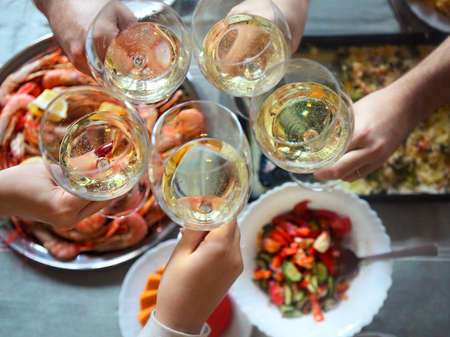 The top view on a table with food and toast with white wine. Gratin, salad and seafood on the table