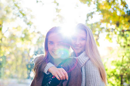 Fashionable beautiful young girlfriends walking together in the autumn park background. Having fun...