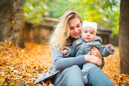 Happy family outdoors. Mother and her little daughter play cuddling on autumn walk in nature...