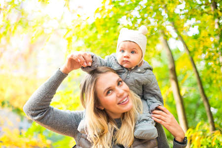 Happy family outdoors. Mother and her little daughter play cuddling on autumn walk in nature...