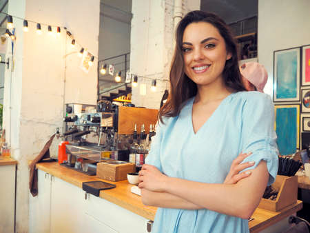 Portrait of a smiling female barista preparing espresso at coffee shopの写真素材