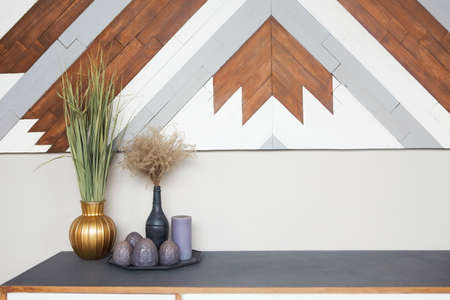 Part of the room interior with wooden commode, vintage vases and candles against the light walls....