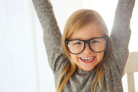 Smiling cute little girl with black eyeglasses over white background. 
Education, school, childhood, people and vision conceptの写真素材