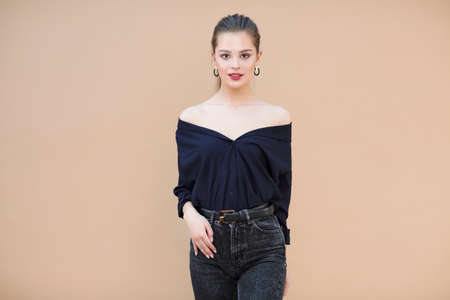 Smiling fashion model wearing navy blue blouse on beige background