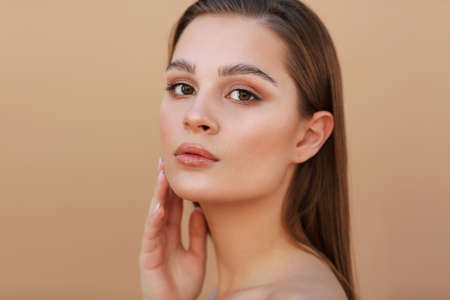 Beautiful Young brunette Woman with Clean Fresh Skin touching own face. Facial treatment. Cosmetology , beauty and spaの写真素材