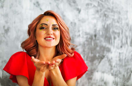 Portrait of a young bright woman with coral colored hairdress with stars make up